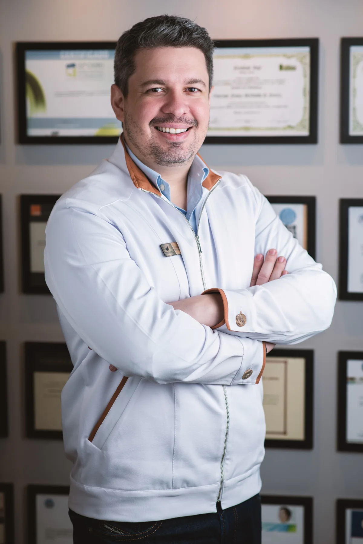 Dr. Gustavo Bertholdo diante de seus diplomas e certificações